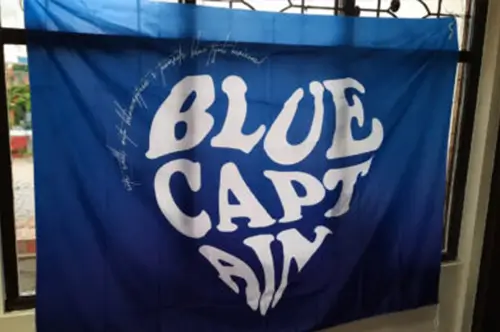 Bendera custom BLUE CAPT FIN berwarna biru dengan tulisan putih berukuran besar, hasil cetak tajam dan warna yang solid dari Nusaflag.
